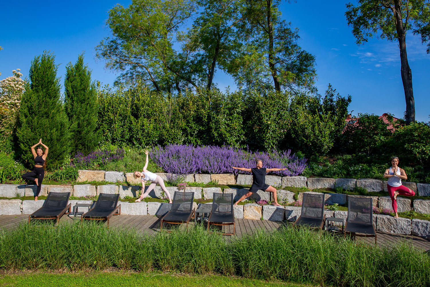 3 Frauen und 1 Mann in unterschiedlichen Yoga - Posen im Freien