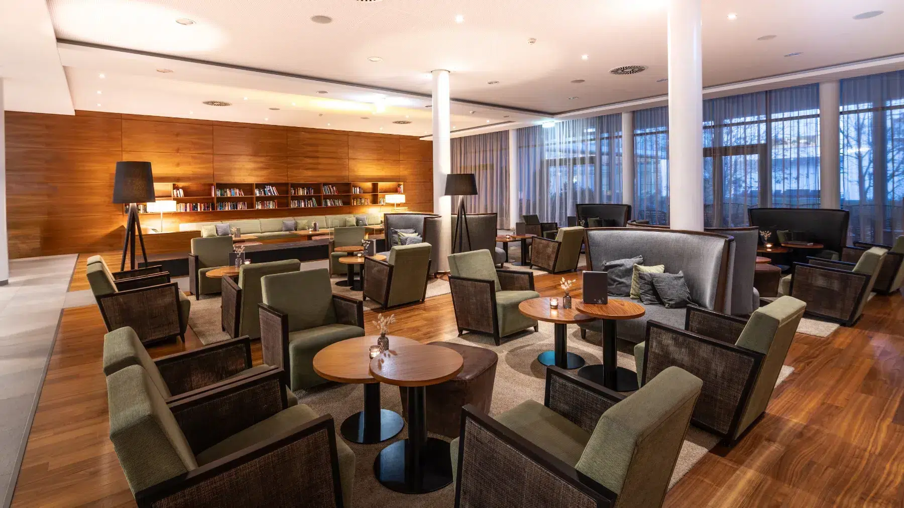 Hotellobby mit vielen grünen Sofasessel und Couchtische, im Hintergrund die Bibliothek