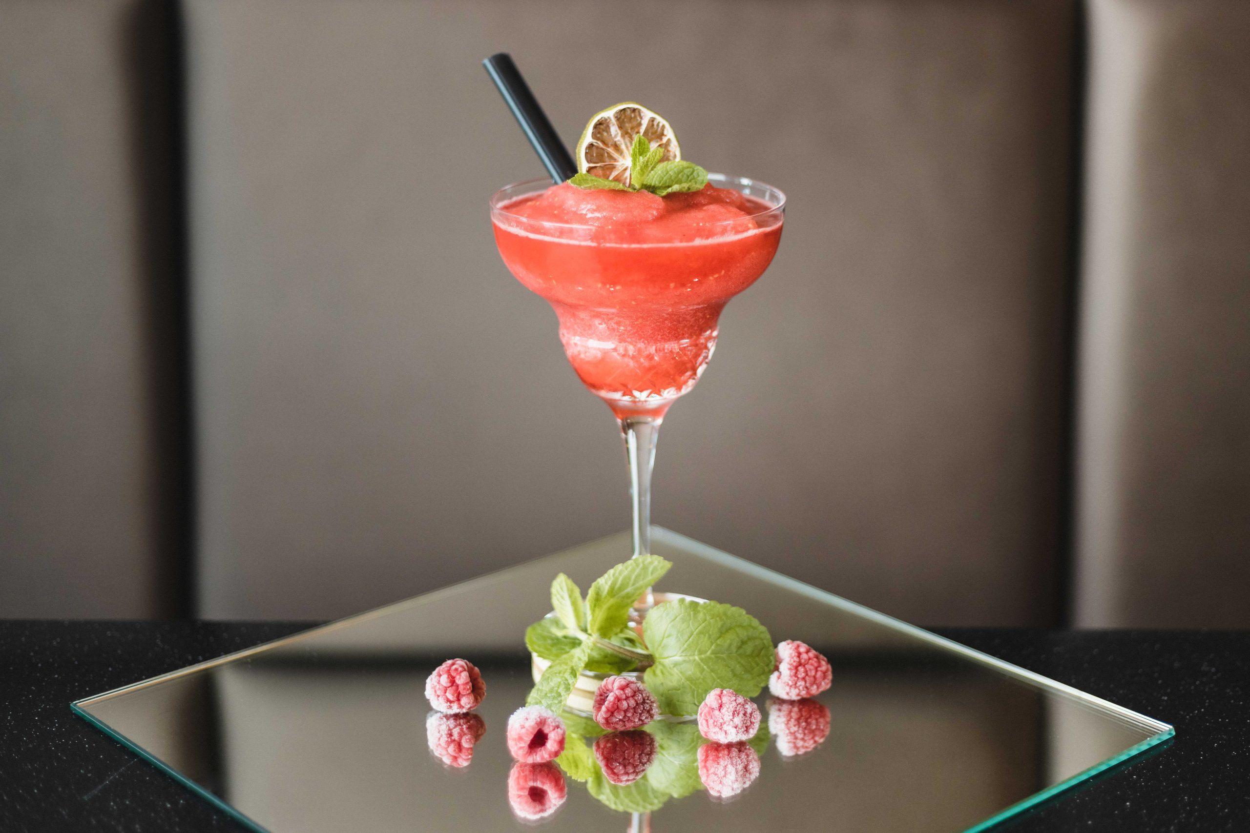 roter Himbeer Cocktail dekoriert mit grünen Blättern und 5 Himberren