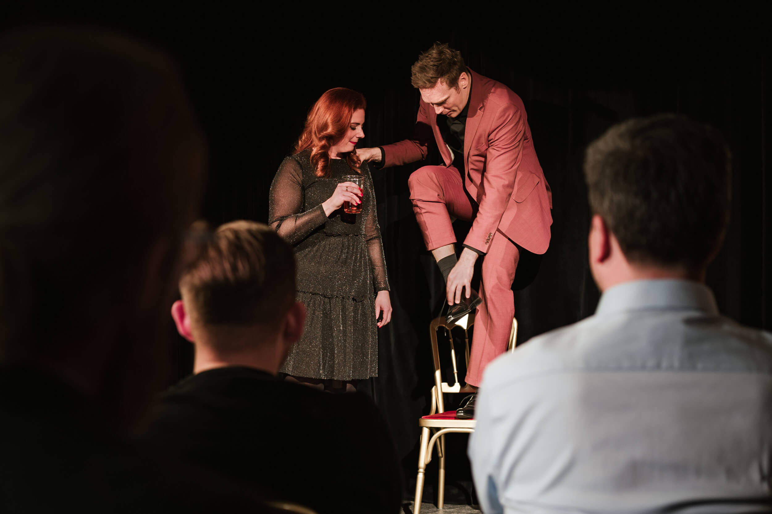 Magier auf der Bühne steht auf Sessel mit Frau